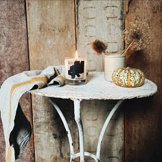 a small table with a candle on it next to a potted plant and a pumpkin