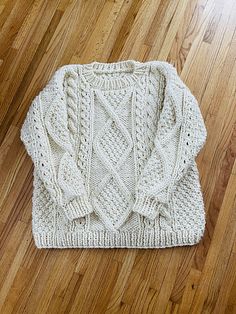 a white sweater sitting on top of a wooden floor