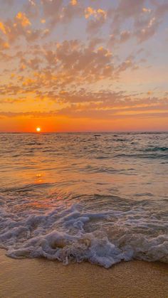 the sun is setting over the ocean with waves coming in