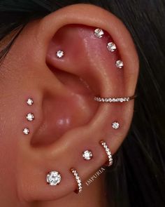 a woman's ear with three different piercings on the middle and one behind her ear