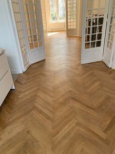 an empty room with wooden floors and white doors leading to another room on the other side