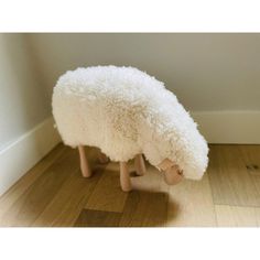 a white sheep sitting on top of a wooden floor