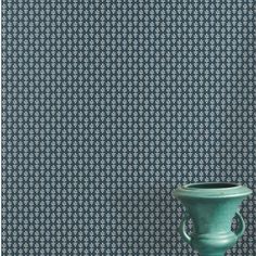 a green vase sitting on top of a table next to a wallpapered wall