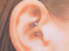 a woman's ear with a single diamond in it