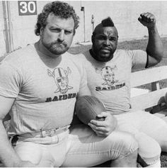 two men sitting on a bench holding footballs