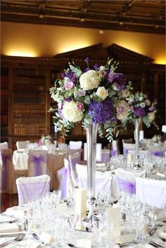 the centerpieces are arranged in tall silver vases with purple and white flowers