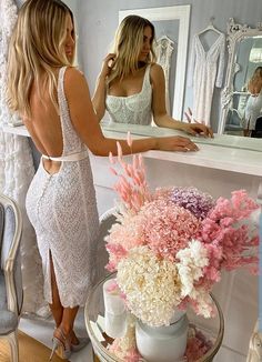 two beautiful women standing in front of a mirror and looking at dresses on the mannequins