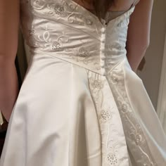 the back of a woman's wedding dress, with her hand on her hip