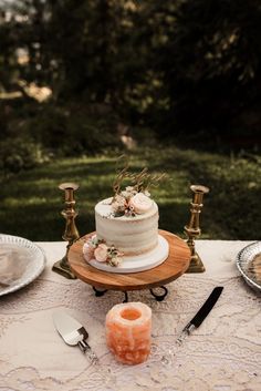 a wedding cake sitting on top of a table next to two candles and some plates