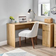 a desk with a laptop on it and a chair next to it in front of a window