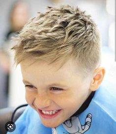 a young boy with blonde hair smiling at the camera