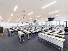 an empty classroom with rows of desks and benches in the center, facing towards windows