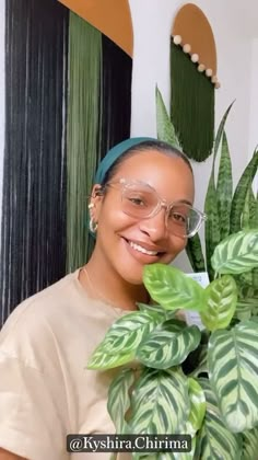 a woman sitting on top of a couch next to a potted plant