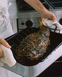 a person in an apron is cleaning a roasting pan with a towel and cloth