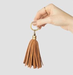 a hand holding a key chain with a tassel