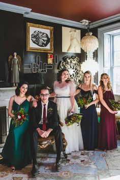 a group of people standing next to each other in front of a fire place holding bouquets