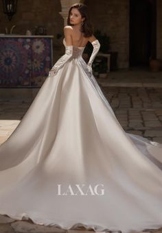 a woman in a wedding dress standing on a stone floor with her back to the camera