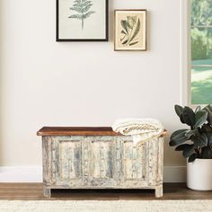 a white bench sitting next to a potted plant on top of a wooden floor