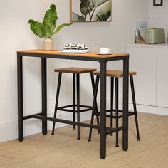 two stools and a table with a plant in the corner next to it on a hard wood floor