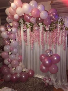 a bunch of balloons that are in front of a curtain and some flowers on the wall