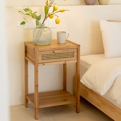 a wooden table with a vase on it next to a bed