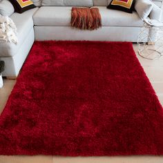 a red rug is on the floor in front of a gray couch and white chair