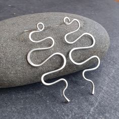 These large sterling silver wave earrings are a real statement piece! They are made from thick silver wire, which I've formed into undulating curves and waves for a bohemian look. I've beaten the tips of the curves to add detail and strength. The earwires are also sterling and are hand forged. Despite their size these earrings are relatively lightweight and have a lovely movement when worn. They'd make a great gift for any fan of contemporary silver jewellery and are sure to get you noticed! Measurements Total length from top of ear wires: 8cm (3 1/8") Wave section length: 6.5cm (2 1/2") Width at widest point: 3cm (1 1/8") Sent nicely gift wrapped in turquoise tissue and an organza pouch, if you prefer a gift box these can be found separately in my shop. Please note this item does not arri Handmade Silver Wavy Jewelry, Handmade Sterling Silver Earrings With A Modern Twist, Contemporary Silver Jewelry, Wave Earrings, Wave Bracelet, Wave Necklace, Bohemian Look, Unusual Design, Lovely Earrings