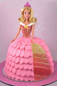 a barbie doll cake with pink frosting and gold decorations