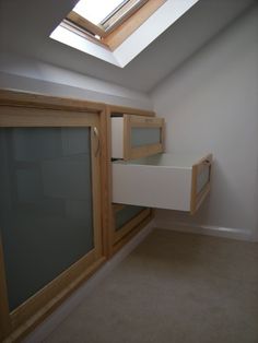 an attic bedroom with skylight and storage drawers on the bottom floor, along with carpeted flooring