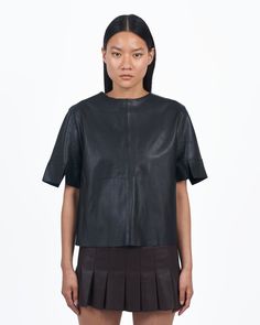 The cure for basic. A slightly oversized boxy leather t-shirt featuring a zip front and short sleeves. Pair with a sleek tonal jumpsuit and knee-high boots for an unexpected monochromatic moment. With a meticulous eye for attention-grabbing detail and quietly refined elegance, Giacca Lusso is for the discerning sophisticate who revels in the balance between chic minimalism and understated opulence. MATERIAL: 100% Leather, unlined for softness FIT NOTES: Relaxed fit. Crafted from the finest secon Leather T Shirt, Vest Layering, Spring Layers, Nyc Shopping, Minimal Chic, Second Skin, Out Of Style, High Boots, Knee High Boots