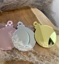 three different colored tags sitting on top of a wooden table next to dried grass and feathers