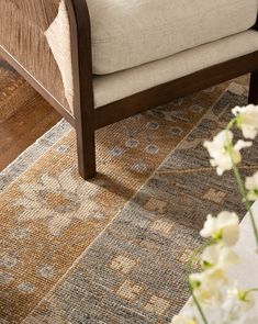 a close up of a chair on a wooden floor with flowers in the foreground