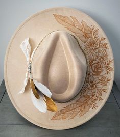 This cream colored floral fedora goes great with any outfit and can also be used for a wedding hat. Made from premium faux suede with cotton and leather banding. She has all the western elements making her wild and bold! I use only the best materials for my hats and each one is handcrafted and uniquely one of a kind.  Show your boho or country flair with this hand drawn hat in assorted colors! Quality vegan suede with a unique artistic burned design. This rancher style, wide brim hat is sure to make a statement. Perfect for the stylish gal who loves one-of-a-kind accessories for the festival, concert, rodeo, girls trip, winery, bridemaid gift, etc. This fedora can be personalized just for you with your own name, date or phrase. Give a gift of fashion and function with this gorgeous rancher Rancher Hats For Women, Wedding Fedora, Western Hats For Women, Western Elements, Wedding Hats For Guests, Custom Cowboy Hats, Hat Inspiration, Rodeo Girls