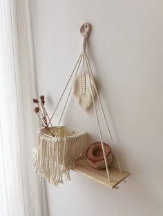 a wall hanging shelf with two macrame baskets on it and a plant in the corner