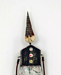 an odd looking doll with a weird hat on it's head and legs, standing in front of a white wall