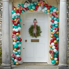 a decorated front door with balloons, wreath and candy canes hanging from it's sides