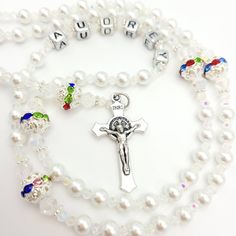 Elegant and personalised Rosary beads made with white pearl beads and silver round beads with multicoloured crystal for Our Father. This would be ideal as a gift for a goddaughter on her baptism. Suitable for many other occasions such as a christening, first holy communion, baptism, confirmation and much more! Add a name and/or Saint pendant to personalise and choose your own centrepiece with a wide variety available. Please select the colour of the Hail Mary beads from drop down menu then choos White Pearl Rosary As A Gift, White Pearl Rosary As Gift, Beaded Rosary For Baptism, White Pearl Rosary For Baptism, White Pearl Jewelry For Birthday, Personalized White Rosary For Confirmation, White Rosary With Round Beads For First Communion, White Rosary With Round Beads For Confirmation, White 8mm Beads Jewelry For Baptism