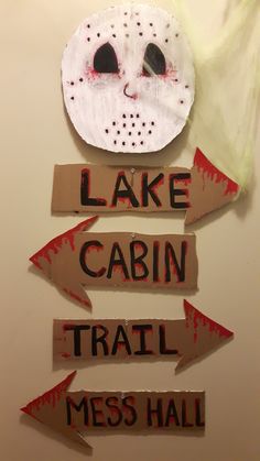 a sign that says lake cabin trail, mess hall and has a mask on it