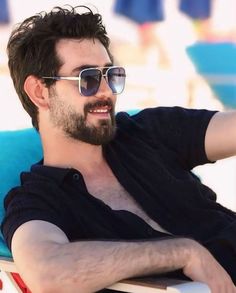 a man sitting on top of a beach chair wearing sunglasses