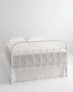 a white metal bed frame with two pillows