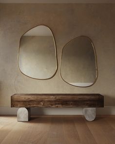 a wooden bench sitting in front of two large mirrors on the side of a wall