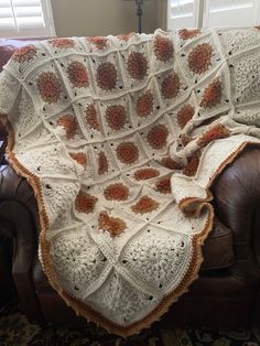 a crocheted blanket sitting on top of a leather chair