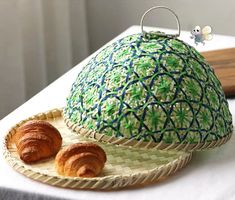 two croissants sitting on a plate next to a green and blue dome