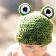 a baby wearing a green crocheted hat with eyes