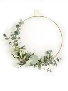 a circular wreath with eucalyptus leaves and other greenery on a white background for an easy diy project