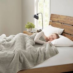 a woman laying in bed under a blanket