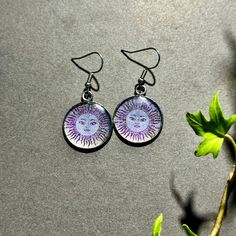 Introducing our radiant stainless steel earrings, laser engraved with a captivating Sun design. Each pair is sealed with a glossy resin finish and infused with shimmering glitter, creating a vibrant and eye-catching accessory. Perfect for adding a touch of sunshine to your everyday style! Artistic Nickel-free Purple Jewelry, Artistic Purple Nickel-free Jewelry, Nickel-free Silver Resin Earrings, Silver Round Resin Earrings, Iridescent Earrings Gift, Iridescent Round Earrings For Gift, Iridescent Earrings For Gift, Nickel-free Iridescent Round Earrings, Artistic Nickel-free Resin Jewelry