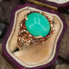 This gorgeous heavily patinated ring features an oval cabochon chrysoprase set with 4 angled prongs atop a freeform gallery. The ring is crafted in 10k yellow gold and is currently a size 6.25. Yellow Gold Emerald Chrysoprase Cabochon Ring, Unique Oval Cabochon Emerald Ring, Heirloom Green Oval Opal Ring, Nature-inspired Green Oval Emerald Ring, Vintage Chrysoprase Ring Jewelry, Vintage Green Oval Opal Ring, Oval Green Chalcedony Rings, Green Oval Chalcedony Rings, Chrysoprase Emerald Ring With Oval Cabochon For Gift