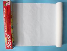 a roll of white paper next to a carton of toilet paper on a blue surface