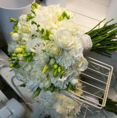 a bouquet of white flowers sitting on top of a metal rack next to a cup